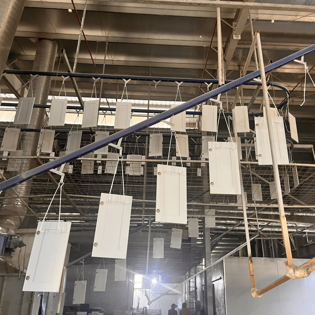 Large-scale shaker cabinet door production line inside VIC Cabinet factory in Vietnam with hanging painted cabinet doors during finishing process